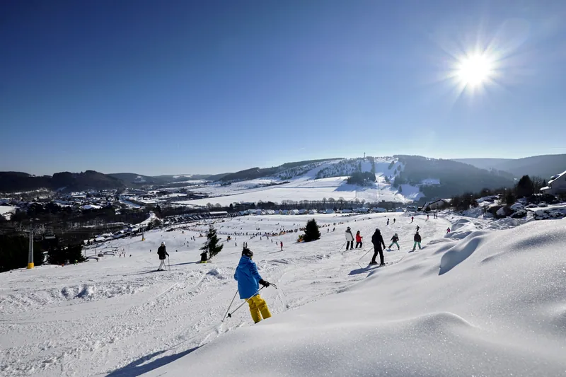 Skifahrer auf einer sonnigen Piste in Willingen, im Hintergrund der Ettelsberg